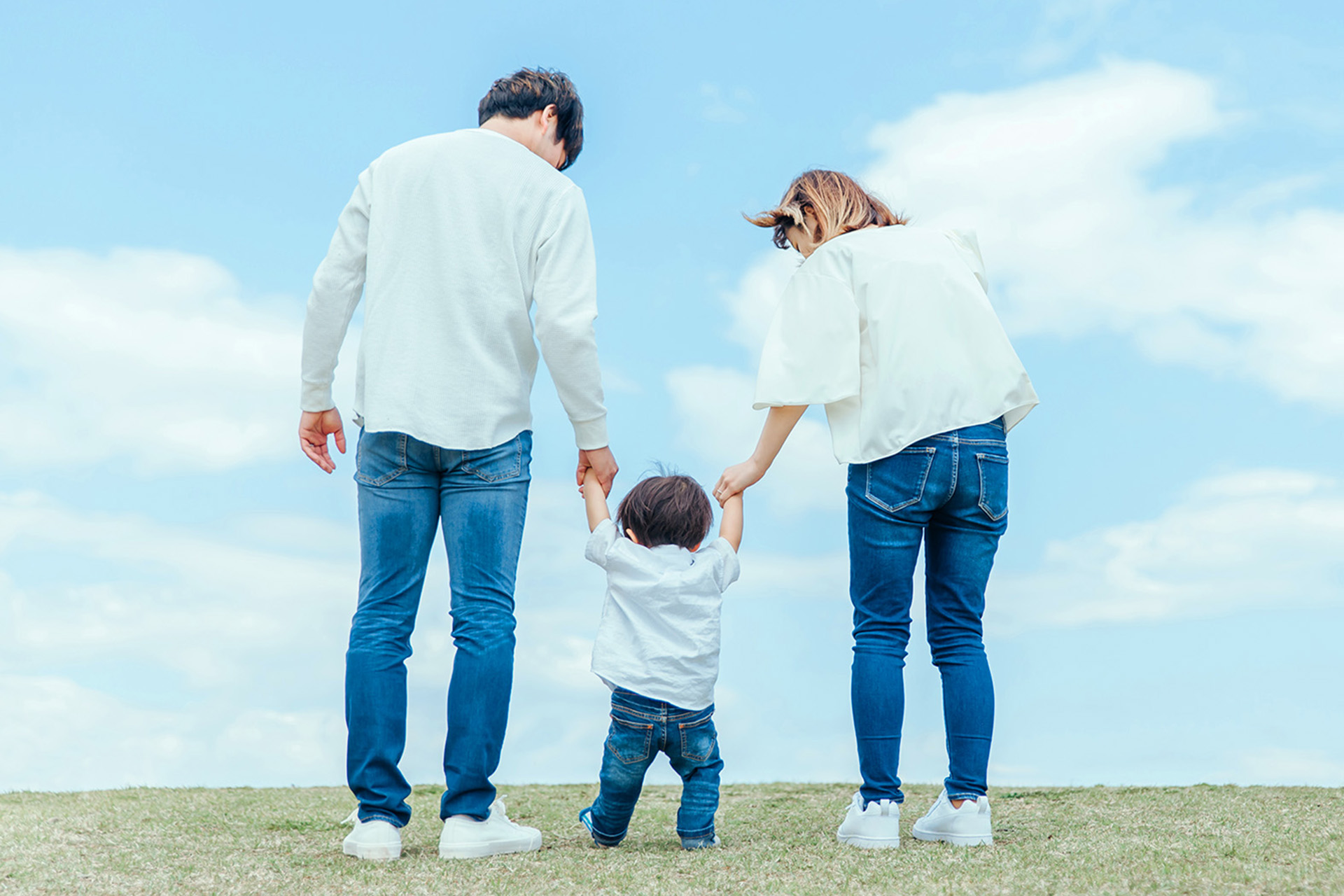 家族3人が手を繋いでいる後ろ姿の画像